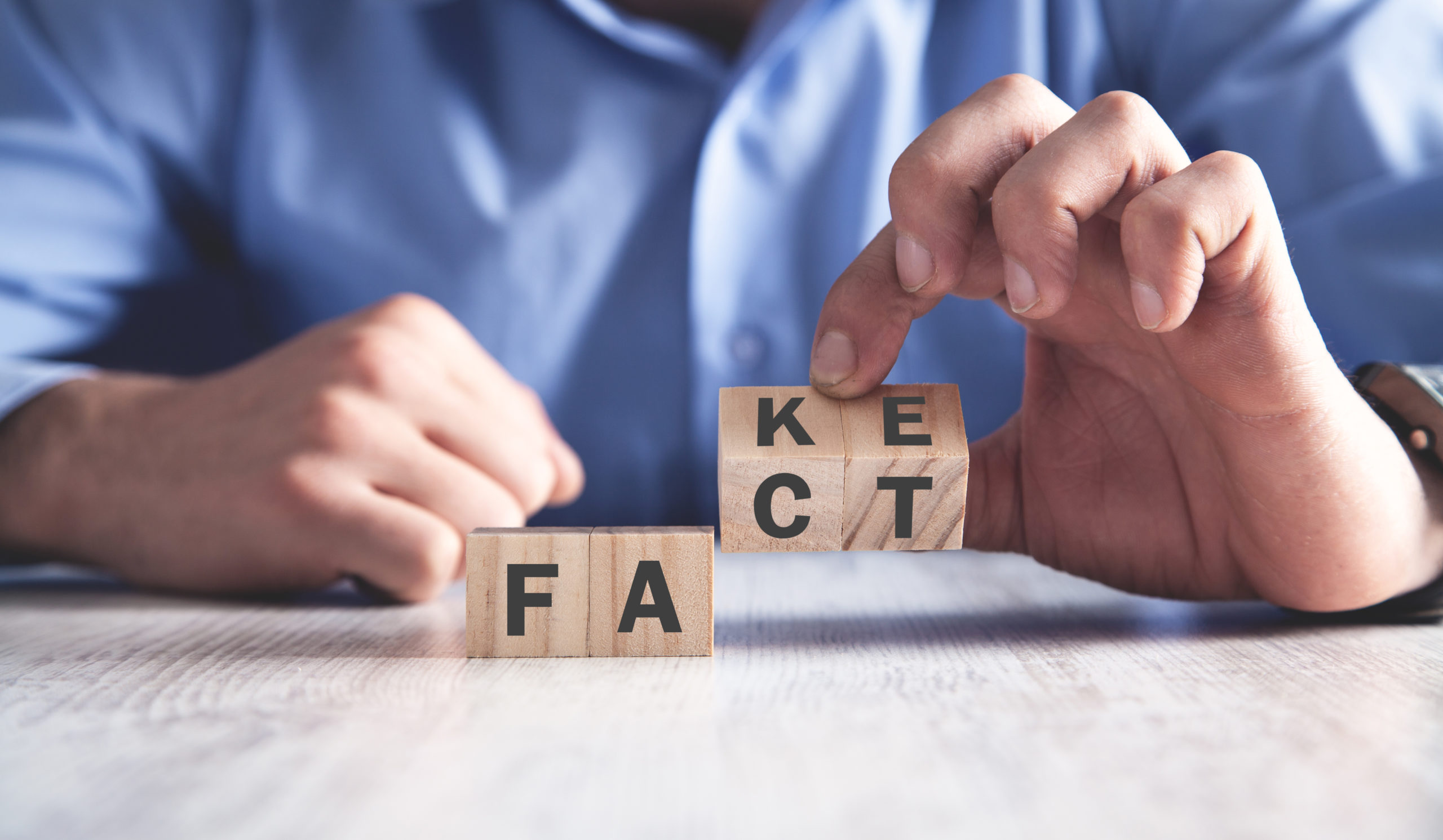 Man holding wooden cubes. Fact or fake. Business concept